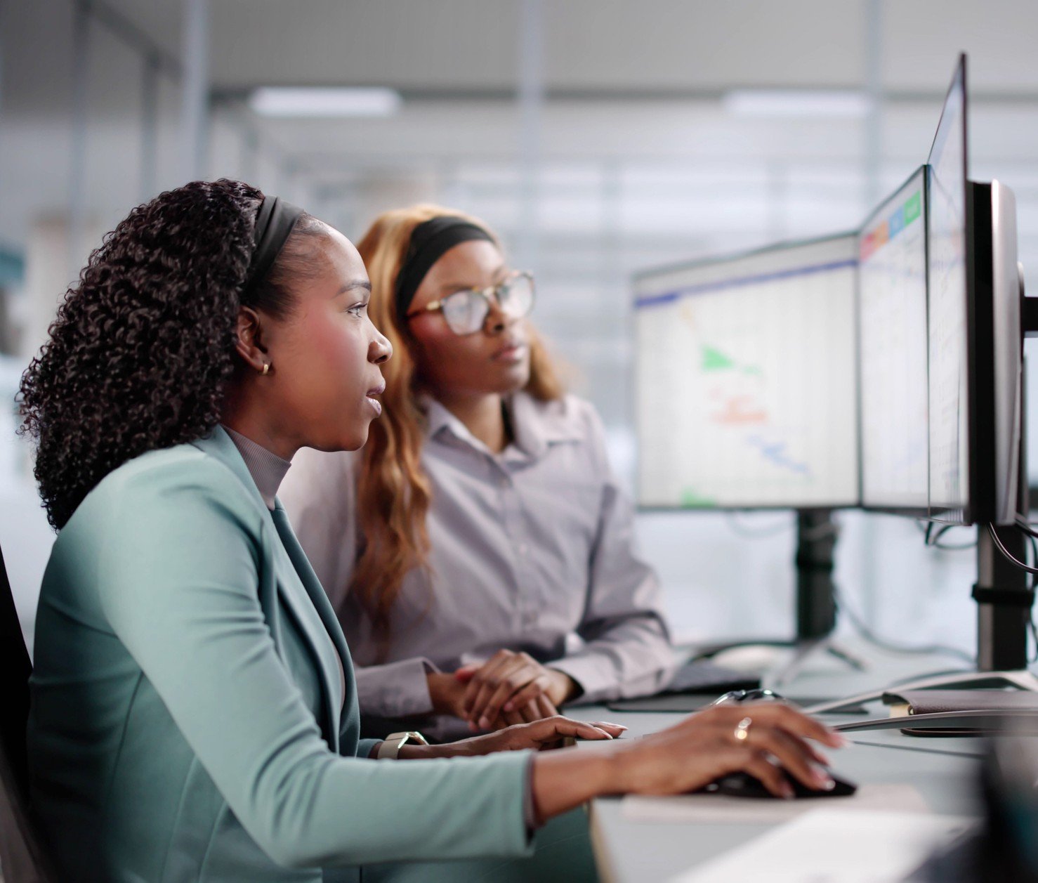 Photo of young woman being shown tasks on computer
