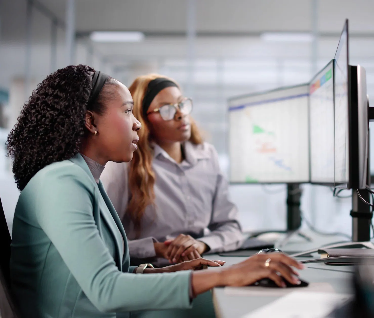 Photo of young woman being shown tasks on computer